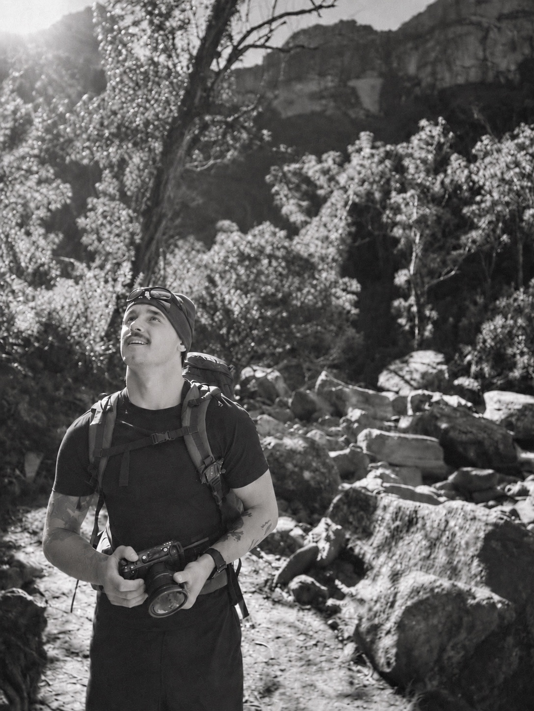 Marley Beavis holding his camera on a rocky trail, photographed in black and white