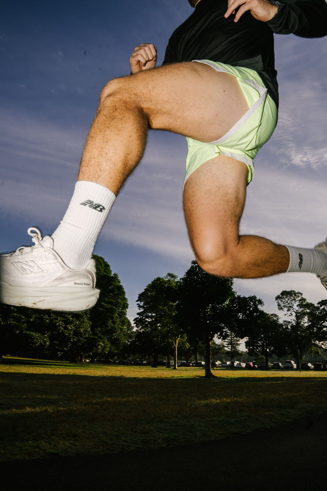 Runner mid-stride against blue sky, shot with flash